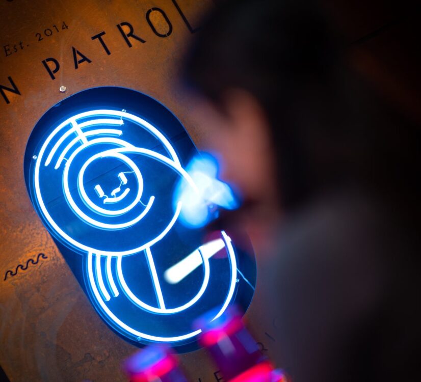 The Dawn Patrol Coffee neon sign at their McLaren Vale roastery, with Est. 2014 visible on the wall behind