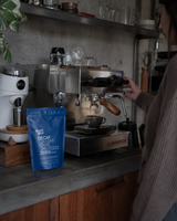 Charlie Black decaf coffee bag beside a person brewing espresso in a home kitchen