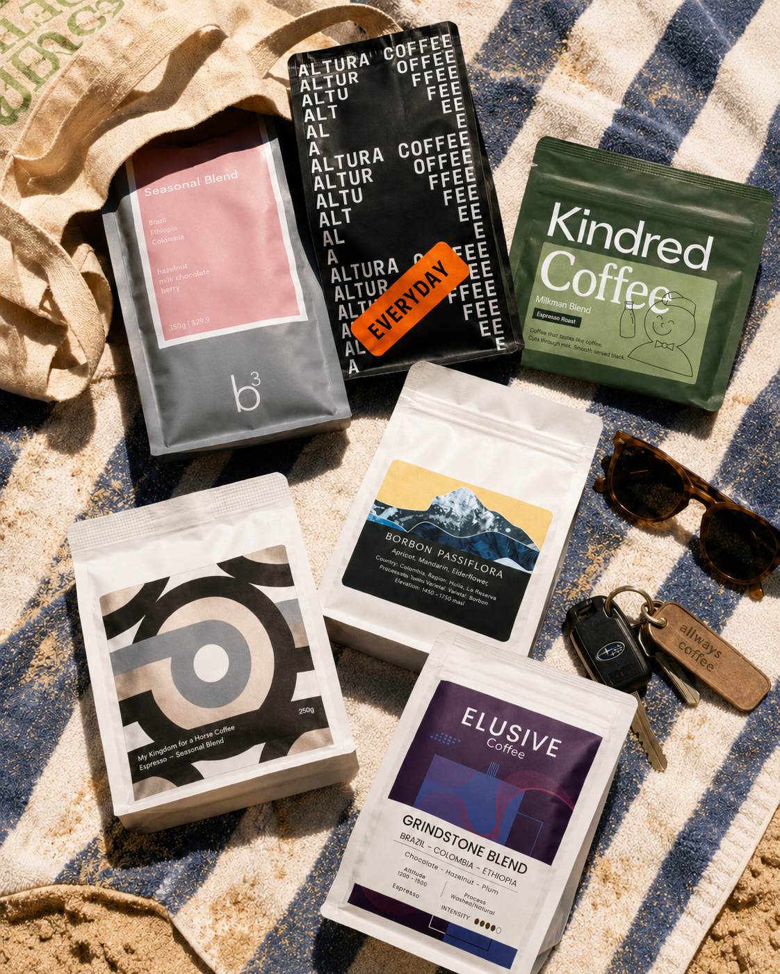 Collection of coffee packages from various brands on a textured surface with sunglasses and keys.